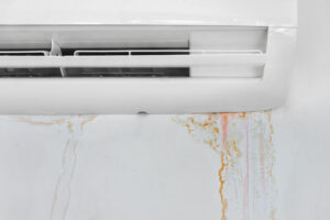 Air conditioner unit with water stains on the wall, indicating potential leakage issues related to HVAC systems.